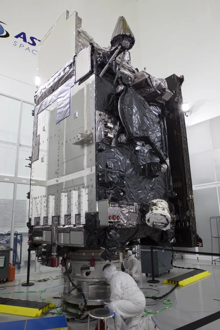 The GOES-R weather satellite, later named GOES-16, standing fully assembled in a clean room in Titusville, Florida, in September 2016, with a technician at its base.