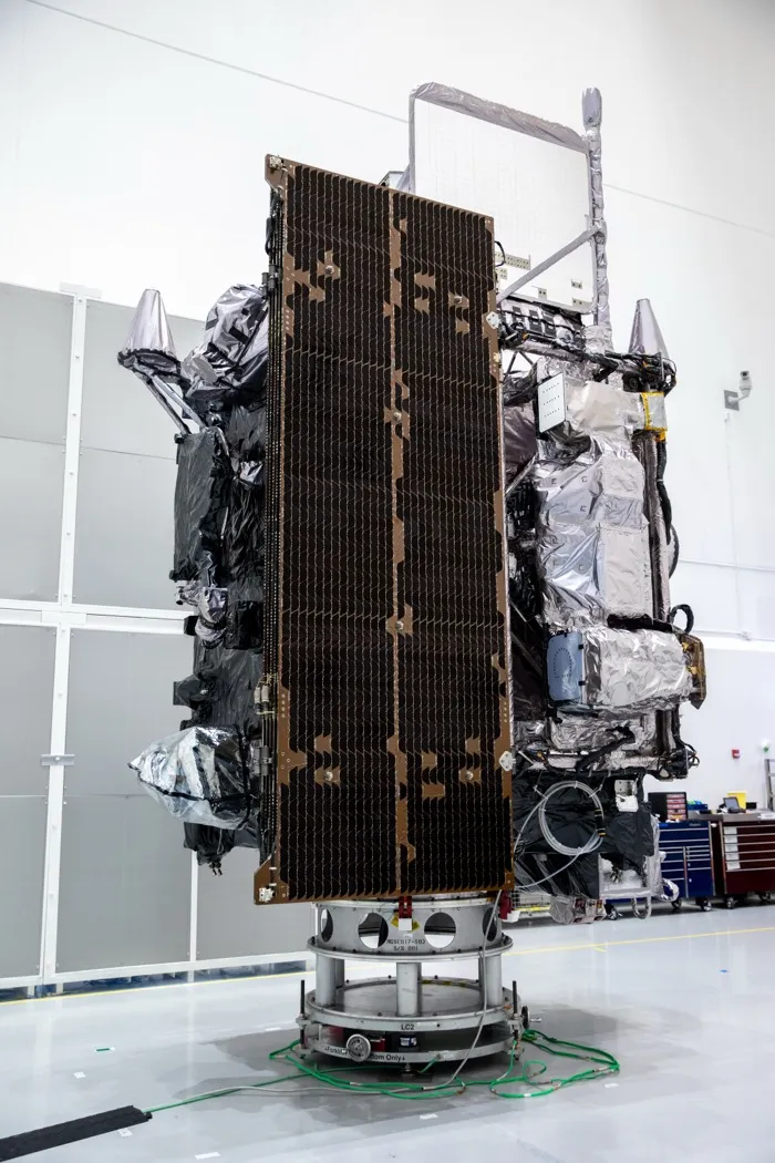 The GOES-T weather satellite, later named GOES-18, standing on its stand in a clean room in Titusville, Florida, in January 2022, its solar array folded against its side.