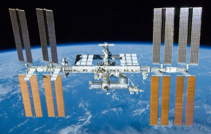 The International Space Station seen from Space Shuttle Atlantis after undocking, its solar arrays spread over the Earth below.