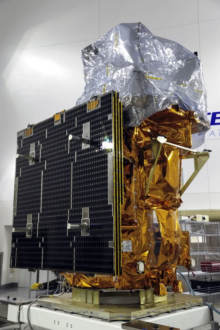 The Landsat 8 satellite in gold thermal blankets, its black solar panel folded against one side and its instruments under silver covers, at Vandenberg before its launch in 2013.