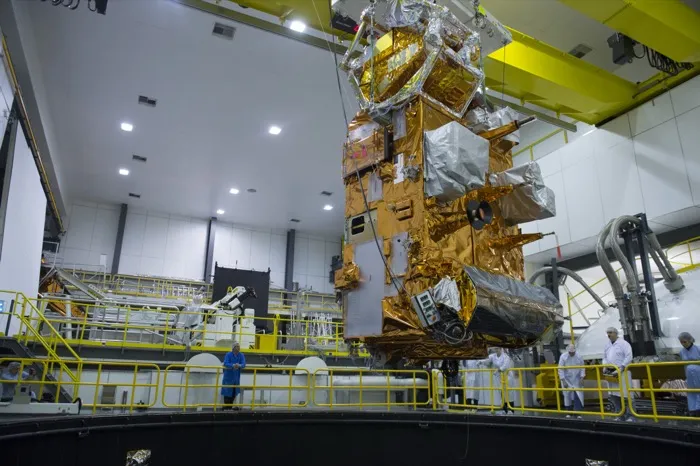 The payload module of Metop-C, wrapped in gold foil, being lowered into ESA’s Large Space Simulator vacuum chamber in the Netherlands for testing in 2017.