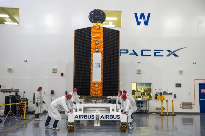 The Sentinel-6 Michael Freilich spacecraft, black solar panels along its sides, wheeled into place for fuelling by technicians in SpaceX’s clean room at Vandenberg in October 2020.